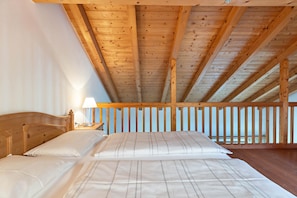 A bedroom with a wooden ceiling, a bed with white linens, and a nightstand with a lamp. - Apartment 'Peintenhof Typ B2' with Mountain View, Balcony & Wi-Fi (Campo Tures)