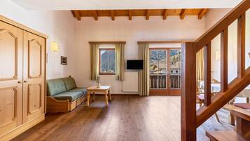 Habitación con suelo de madera, sofá, una mesa y televisor.