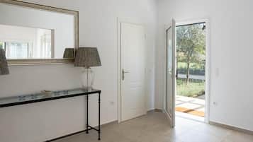 A hallway with a door, a glass door leading outside, and a console table with a lamp.