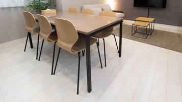 A conference room with a large table and chairs, a small table, a TV, and a plant.