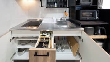 A compact kitchen with a built-in microwave, a sink, and a drawer with utensils.