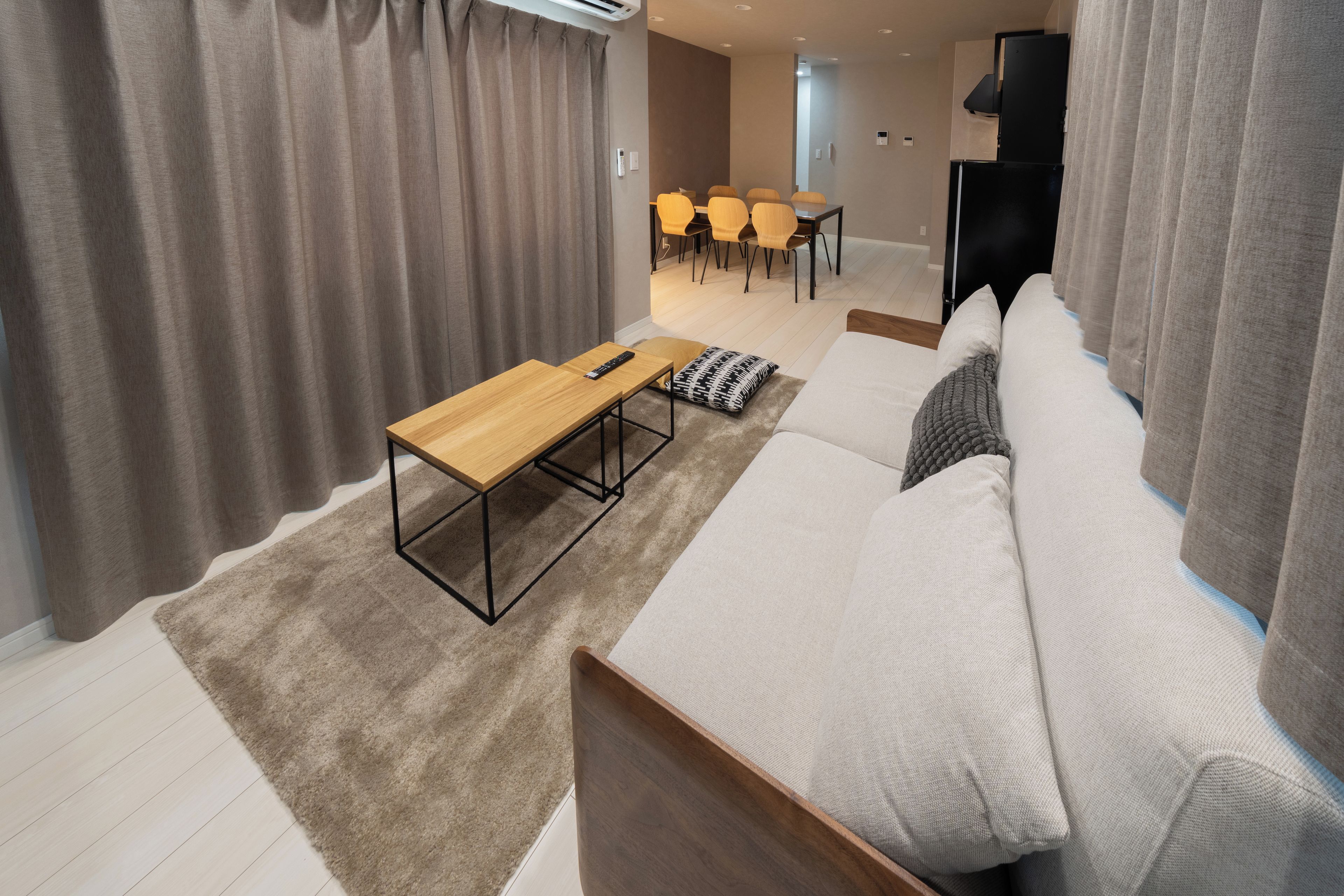 A modern living room with a sofa, a wooden coffee table, and a TV.