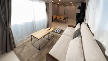 Ein modernes Wohnzimmer mit einer Couch, einem Couchtisch aus Holz und einem Essbereich mit Stühlen.