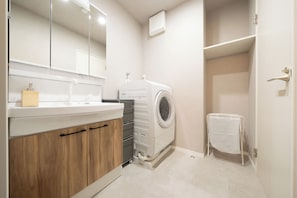 Um banheiro moderno com máquina de lavar embutida, um espelho e porta-toalhas.
