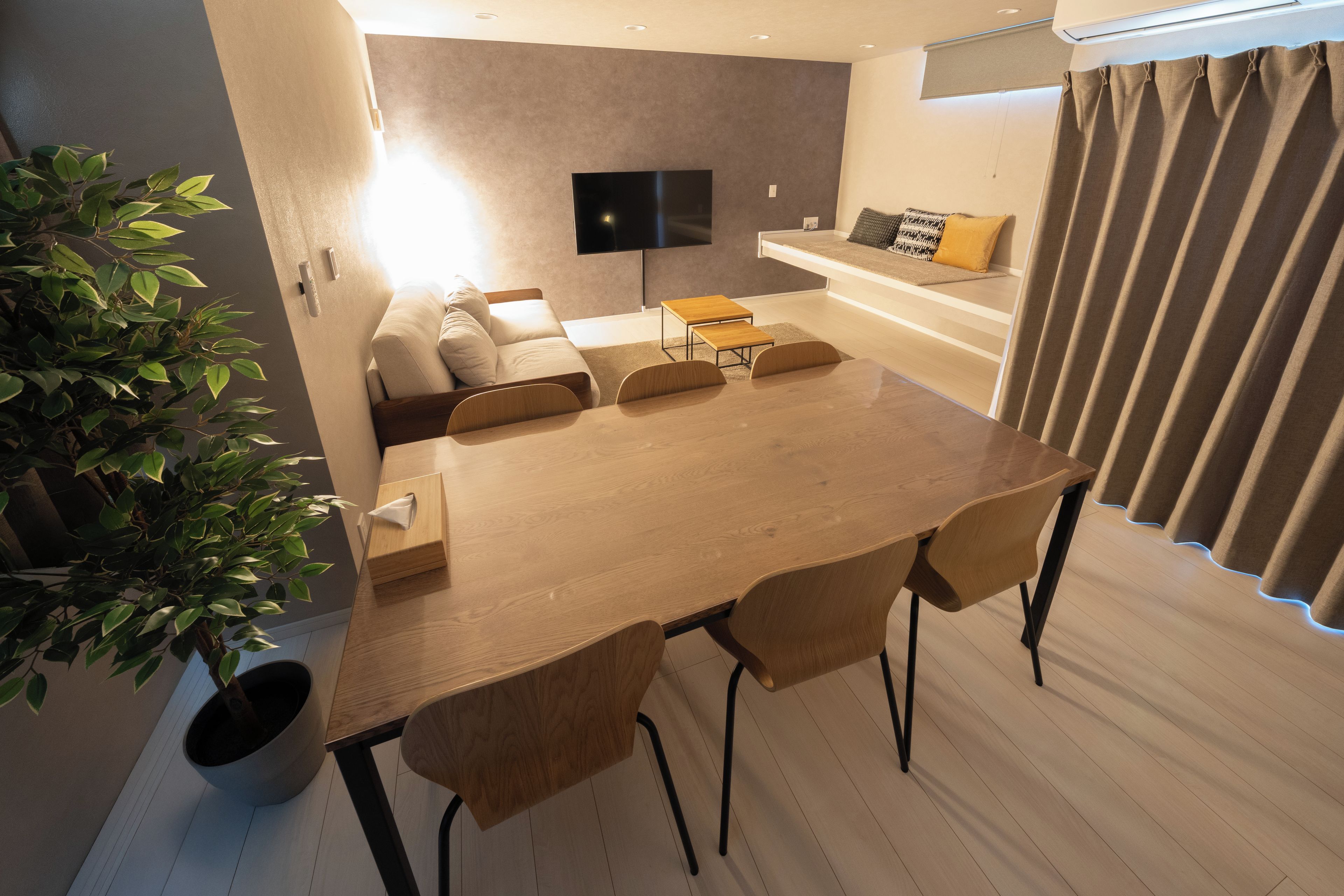 Una sala moderna con una mesa de comedor de madera, un sofá y una televisión.
