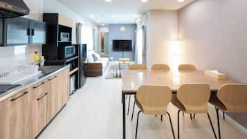 Una cocina moderna con electrodomésticos integrados, un comedor con sillas de madera y un televisor de pantalla plana montado en la pared.