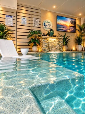 A swimming pool with clear water, a waterfall feature, and a sunset view. - Beach, Pizza Oven, Saltwater Heated pool, Hot Tub (Hilton Head Island)