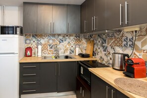 A compact kitchen with modern appliances, a patterned backsplash, and dark cabinetry. - Apartment 'George House' with Balcony, Wi-Fi and Air Conditioning (Θεσσαλονίκη)