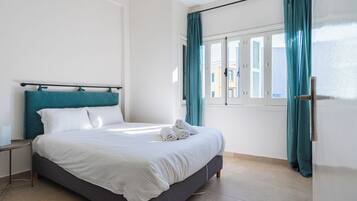 Une chambre d’hôtel avec un lit, une table de chevet, une fenêtre avec des rideaux et une porte.