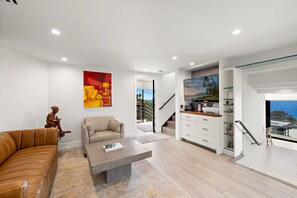 A modern living room with a leather sofa, a coffee table, and a painting on the wall. - Private Ocean-View Guest Casita, South Laguna Beach (Laguna Beach)