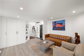 A modern living room with a brown leather sofa, a coffee table, and a painting on the wall. - Private Ocean-View Guest Casita, South Laguna Beach (Laguna Beach)