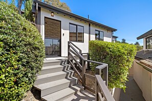 A modern two-story house with a wooden staircase leading to the front door, surrounded by well-maintained hedges. - Private Ocean-View Guest Casita, South Laguna Beach (Laguna Beach)