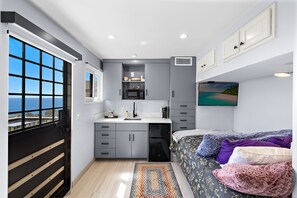A compact kitchen with a view of the sea, a bed with multiple pillows, and a mounted TV. - Private Ocean-View Guest Casita, South Laguna Beach (Laguna Beach)