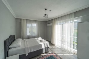A bedroom with a large bed, sheer curtains, and a view of greenery outside. - Villa Dogakent 3 - Four Bedroom Villa, Sleeps 8 (Okçular)
