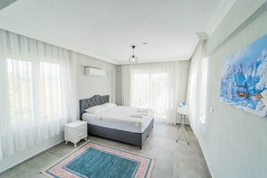 Un dormitorio moderno con una cama grande, una mesita de noche, una pequeña mesita auxiliar y un cuadro en la pared.