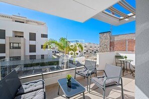 Eine moderne Außenpatio mit Glasgeländern, Metallmöbeln und Blick auf angrenzende Gebäude.