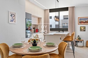 Ein moderner Essbereich mit einem runden Tisch, Stühlen und einem Blumenstrauß.