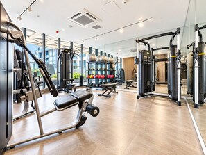A modern gym with various exercise equipment, large windows, and a clean, spacious interior. - Koala Stay Luxury CBD Retreat with Skyline Views (Adelaide)