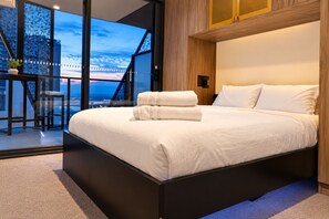 A modern bedroom with a large bed, a view of the cityscape, and a balcony with a chair. - Koala Stay Luxury CBD Retreat with Skyline Views (Adelaide)