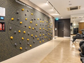 A climbing wall with various holds, a reception area, and exercise equipment. - Koala Stay Luxury CBD Retreat with Skyline Views (Adelaide)