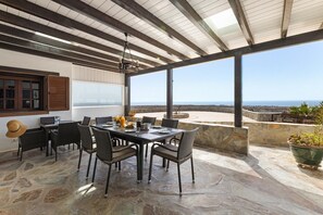 Eine Terrasse im Freien mit Esstisch, Steinböden und Meerblick.