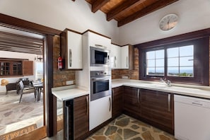A modern kitchen with built-in appliances, a stone backsplash, and a view through the window. - Villa Finca Vicela - Five Bedroom Villa, Sleeps 10 (Tias)