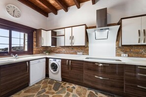 A modern kitchen with a stone backsplash, wooden cabinets, a built-in dishwasher, and a large window. - Villa Finca Vicela - Five Bedroom Villa, Sleeps 10 (Tias)