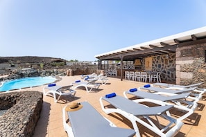 A poolside area with lounge chairs and a stone wall. - Villa Finca Vicela - Five Bedroom Villa, Sleeps 10 (Tias)