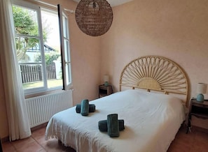 A bedroom with a large bed, a window, a bedside table, and a hanging light fixture. - Family home 500 meters from the beach, sleeps 6 (Andernos-les-Bains)