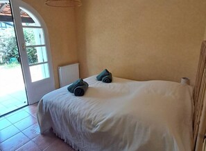 Ein Schlafzimmer mit einem Bett, einem Heizkörper und einer Tür, die zu einem Außenbereich führt.