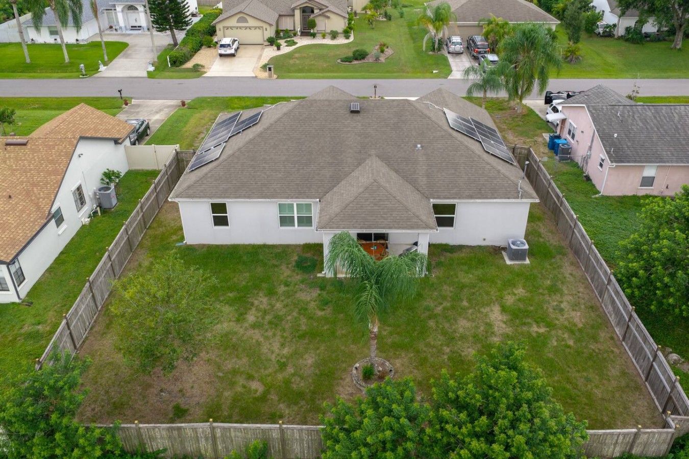 A single-story house with a fenced yard, solar panels on the roof, and a small front porch.