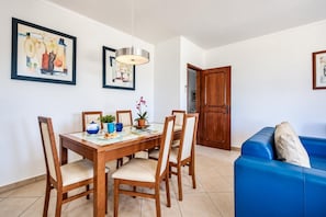 Ein Essbereich mit einem Holztisch, Stühlen und einer blauen Couch im Hintergrund.