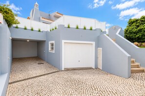 A modern building with a white facade, a garage, and a cobblestone driveway. - Villa Silva Balbina - Four Bedroom Villa, Sleeps 8 (Albufeira)