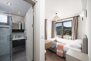 Habitació d'hotel moderna amb llit, tauleta de nit i vista a l'exterior.