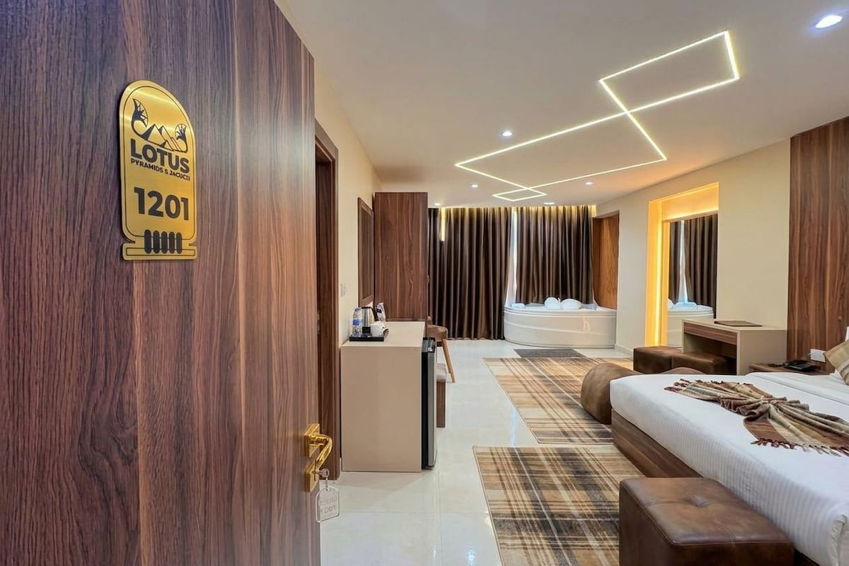 Habitació d'hotel moderna amb una paret decorativa de fusta, un llit, un escriptori i un bany amb banyera.