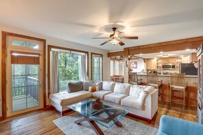 A spacious living area with a large sectional sofa, a glass coffee table, and a ceiling fan. - Mtn-View Condo w Private Balcony in Burnsville (Burnsville)