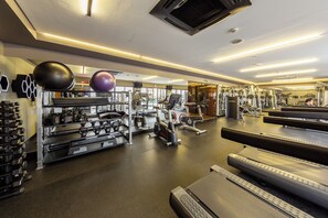 Ein Fitnessstudio mit verschiedenen Trainingsgeräten, darunter Laufbänder, Kraftgeräte und Kurzhanteln.