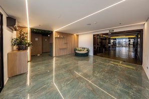 Eine moderne Lobby mit Marmorboden, Holzvertäfelung, einer Rezeption und einer Sitzecke.