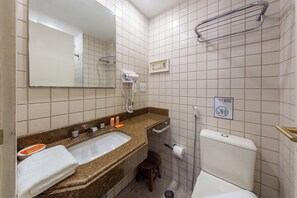 Ein Badezimmer mit Waschbecken, Spiegel, Handtuchhalter, Toilette und Duschbereich.