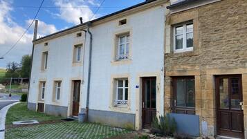 Un immeuble résidentiel de deux étages, doté d’une allée pavée et d’un petit jardin.