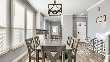 Un comedor con una mesa larga y sillas, un candelabro y una cocina al fondo.