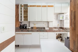 A modern kitchen with white cabinets, a granite countertop, and a built-in dishwasher. - Spacious 1BR Near Metro Copacabana Br1102 (Rio de Janeiro)