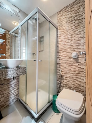 Et moderne badeværelse med et glasafskærmet brusebad, en vask og et toilet.
