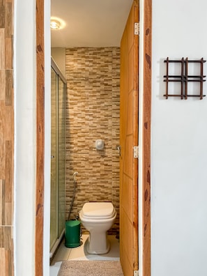 A small bathroom with a toilet, a shower, and a wooden door. - Spacious 1BR Near Metro Copacabana Br1102 (Rio de Janeiro)