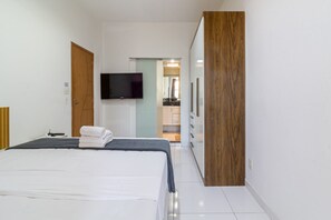 A hotel room with a bed, a television mounted on the wall, and a wooden door. - Spacious 1BR Near Metro Copacabana Br1102 (Rio de Janeiro)