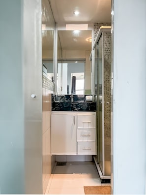 A narrow kitchen with white cabinets, a black countertop, and a glass door refrigerator. - Spacious 1BR Near Metro Copacabana Br1102 (Rio de Janeiro)