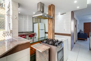 A modern kitchen with a gas stove, stainless steel range hood, and a refrigerator. - Spacious 1BR Near Metro Copacabana Br1102 (Rio de Janeiro)
