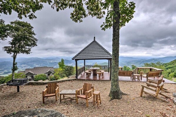 Ein Pavillon mit Tisch und Stühlen, umgeben von einer Terrasse mit Blick auf die Berge.