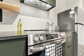 A modern kitchen with a stainless steel range, oven, and refrigerator. - The Cardinal | Wooded Stay Near Downtown + Trails (Bentonville)