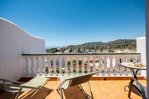 A balcony with a view of a coastal town, white balustrades, and a table with chairs. - Casa Alborán | Jacuzzi | Billiard | BBQ | Sea view (Málaga)